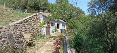 a stone house on a hill next to a stone wall at Can Parròquia in Sant Esteve de Palautordera