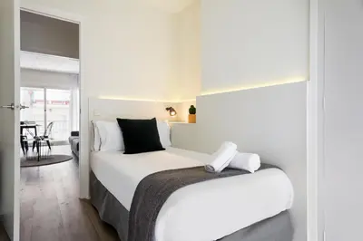 a bedroom with a large white bed with black pillows at Sitges Group Calm Beach in Sitges