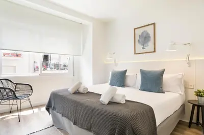 a bedroom with a bed and a chair and a window at Sitges Group Calm Beach in Sitges