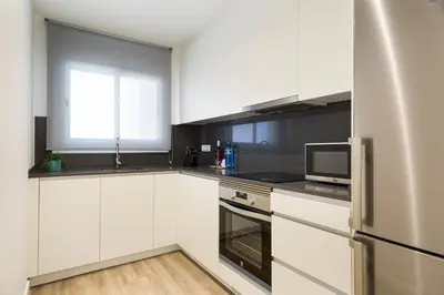 a white kitchen with a refrigerator and a microwave at Sitges Group Calm Beach in Sitges