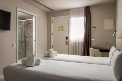 two beds in a hotel room with a bathroom at Arya Stadium Hotel in Barcelona