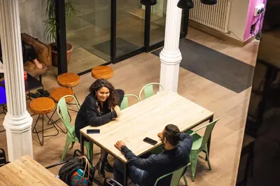 two people sitting at a table in a room at Safestay Barcelona Gothic in Barcelona