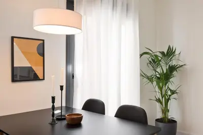 a dining room table with a lamp and a plant at Urban Chill Apartments by Olala Homes in Hospitalet de Llobregat