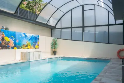 an indoor swimming pool with a large window and a large swimming pool at Luxurious Villa Marly II piscina climatizada in Castelldefels