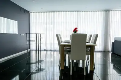 a dining room table with white chairs and a red flower on it at Luxurious Villa Marly II piscina climatizada in Castelldefels