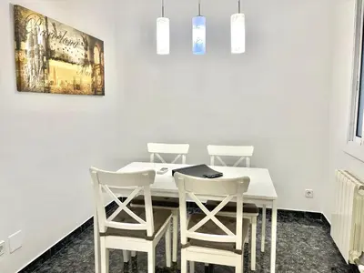 a dining room with a white table and four white stools at Elegantniy Poble Sec in Barcelona