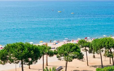 a beach with a bunch of people and umbrellas at Hotel Sabiote in Pineda de Mar