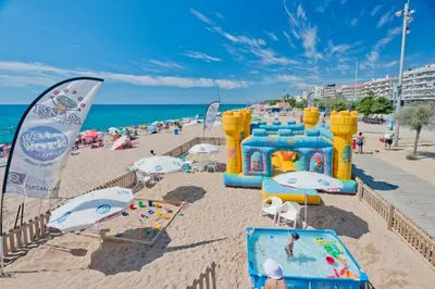 a beach with a group of people on the beach at Hotel Sabiote in Pineda de Mar