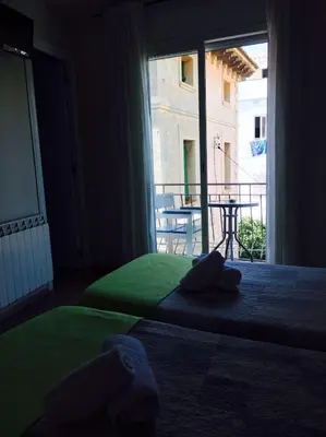 two beds in a room with a view of a balcony at Hostal Termes in Sitges