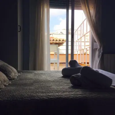 two people laying on a bed in front of a window at Hostal Termes in Sitges