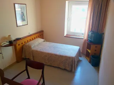 a small bedroom with a bed and a window at Hotel Montmeló in Montmeló