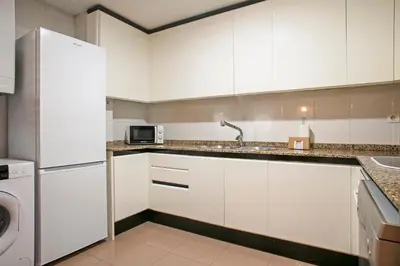 a white kitchen with a sink and a microwave at Alcam El Coll in Barcelona
