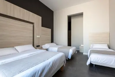two beds in a room with white sheets and white blankets at Plaza Goya Rooms in Barcelona