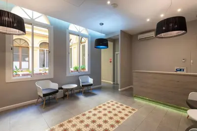 a waiting room with chairs and a table and windows at Plaza Goya Rooms in Barcelona