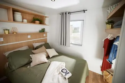 a small bedroom with a green bed and a window at Camping Vilanova Park in Vilanova i la Geltrú