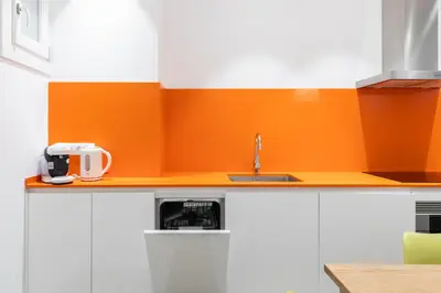 a kitchen with a sink and an orange wall at Cosmo Apartments Marina – Auditori in Barcelona