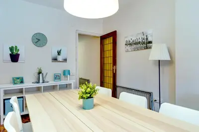 a dining room with a wooden table and white chairs at Spacious 4 Bedroom Apartment Fira BCN & Camp Nou in Barcelona