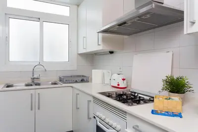 a white kitchen with a sink and a stove at Spacious 4 Bedroom Apartment Fira BCN & Camp Nou in Barcelona