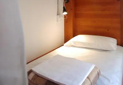 a bedroom with a white bed with a wooden headboard at Ten To Go Hostel in Barcelona