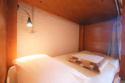 a small room with a bed in a wooden room at Ten To Go Hostel in Barcelona
