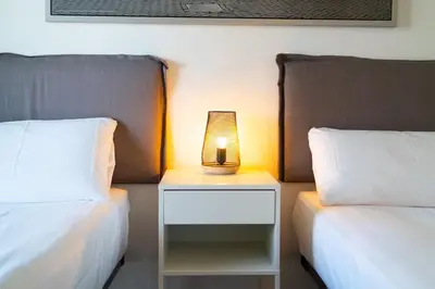 a lamp sitting on a night stand between two beds at Unique Rentals-Seafront Luxe Suites in Barcelona