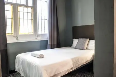 a bedroom with a white bed with two windows at Hostal Boutique Khronos in Barcelona