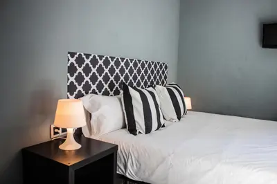a bed with black and white pillows and a table with a lamp at Hostal Boutique Khronos in Barcelona