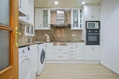 a kitchen with white cabinets and a washer and dryer at Alcam Calabria in Barcelona