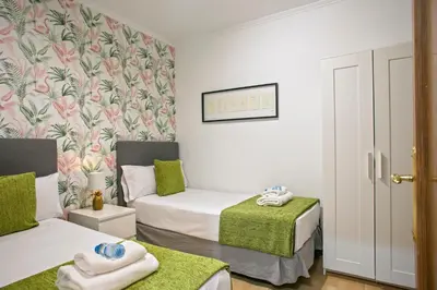 a small room with two beds and a green blanket at Alcam Calabria in Barcelona
