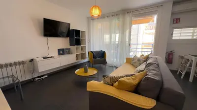a living room with a couch and a tv at Sunny Flat in Sitges 30 Seconds to Beach, Balcony & Sea Views! in Sitges