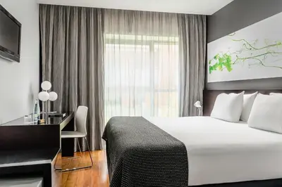 a hotel room with a bed and a desk and a window at Ikonik Lex in Hospitalet de Llobregat