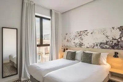 a bedroom with a white bed and a window at Aspasios Poble Nou Apartments in Barcelona