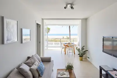 a living room with a couch and a view of the ocean at Sunny Beachfront Escape in Castelldefels