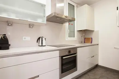 a white kitchen with white cabinets and a stove at Akira Flats Roger de Flor Chic apartment in Barcelona