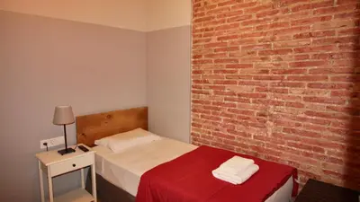 a bedroom with a bed and a brick wall at Paraiso Hostel in Barcelona