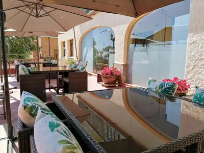 an outdoor patio with chairs and an umbrella at Cal Músic B&B in Premia de Dalt
