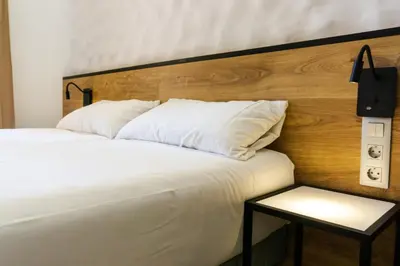 a bedroom with a white bed with a wooden headboard at Fontanella Green House in Barcelona