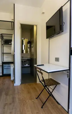 a room with a table and a television on a wall at Fontanella Green House in Barcelona
