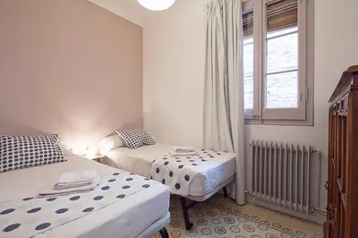 two beds in a small room with a window at Central and Spacious Family Apartment in Barcelona