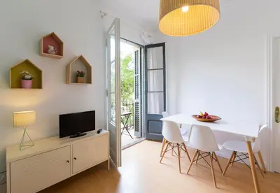 a dining room with a white table and chairs and a television at Cozy Flat With Unbeatable Views to Sagrada Familia in Barcelona