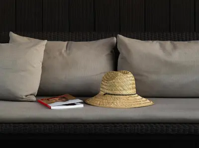 a straw hat and a book on a couch at Hotel Arconte, Adults Only in Barcelona