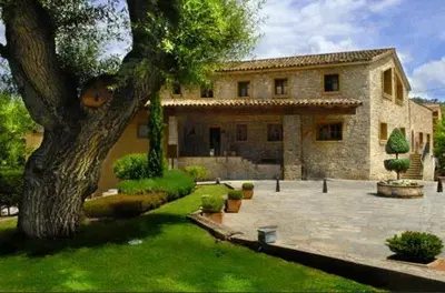 a large stone house with a tree in the yard at Fonda La Masia Del Sola in Monistrol de Calders