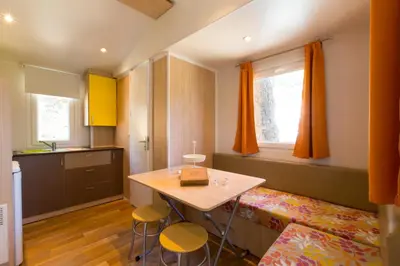 a small kitchen with a table and two stools at Camping Bungalows El Far in Calella