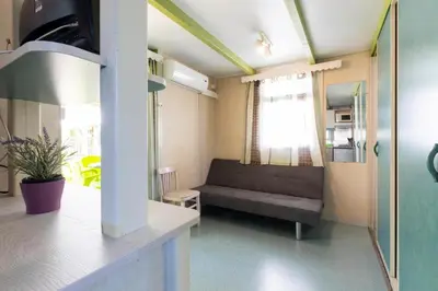 a living room with a couch and a kitchen at Camping Bungalows El Far in Calella