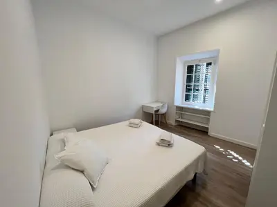 a white bedroom with a bed and a window at Hostal del Palau in Barcelona
