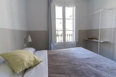 a white bedroom with a bed and a window at Hostal Hera in Barcelona
