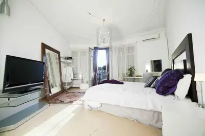 a white bedroom with a large bed and a flat screen tv at Balcones y Vistas en el Centro de la Ciudad in Barcelona
