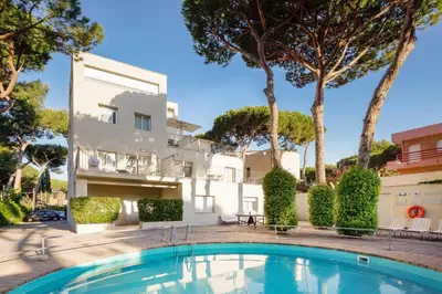 a villa with a swimming pool in front of a building at Apartamentos Porta Coeli in Castelldefels
