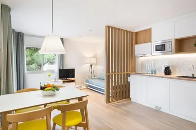 a kitchen and living room with a table and chairs at Apartamentos Porta Coeli in Castelldefels