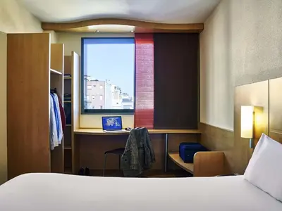 a bedroom with a bed and a desk with a laptop at Ibis Barcelona Centro (Sagrada Familia) in Barcelona